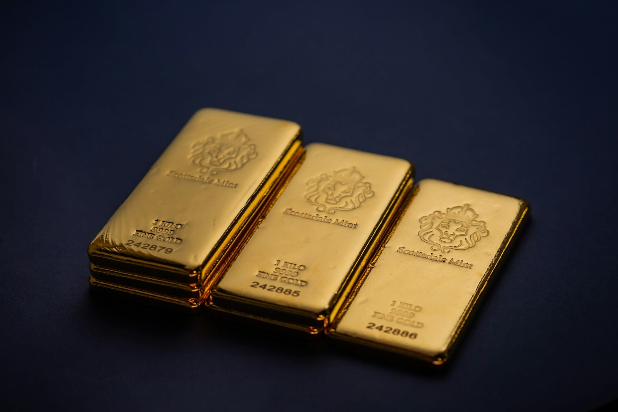 Three kilo gold bars on a dark surface