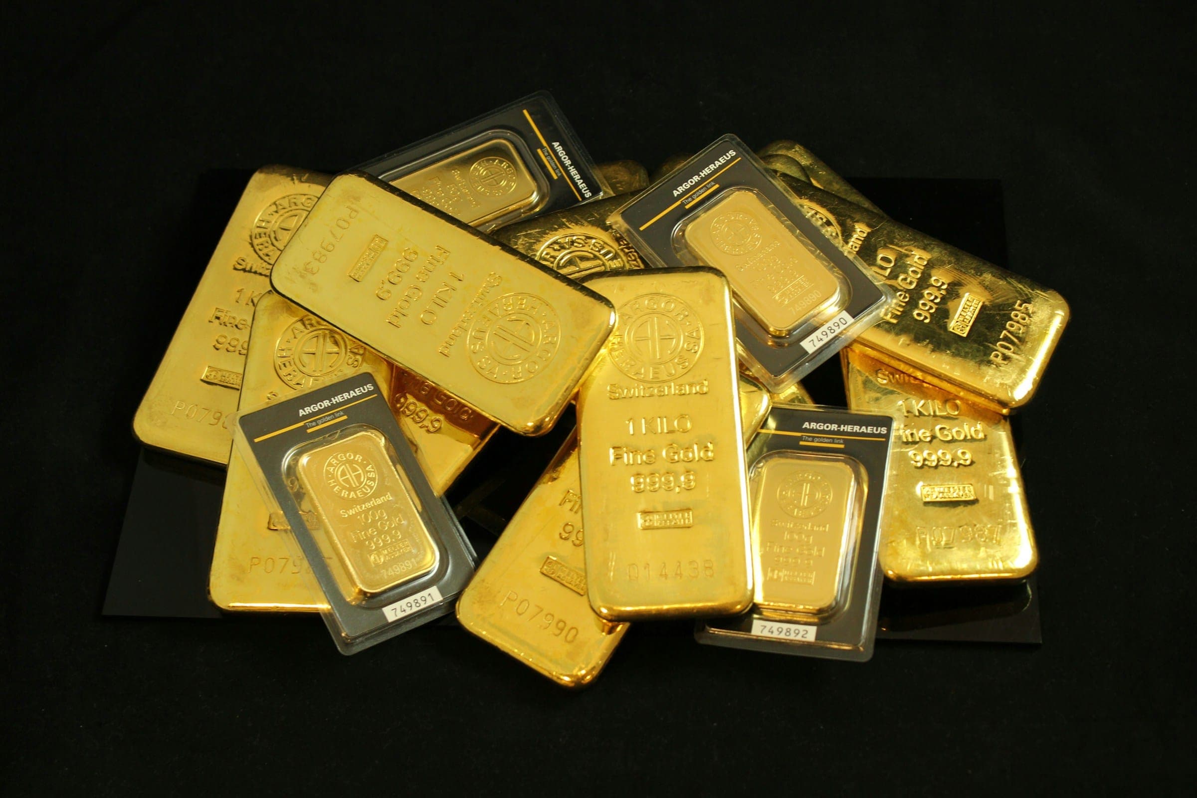 Gold bullion bars and coins on black
