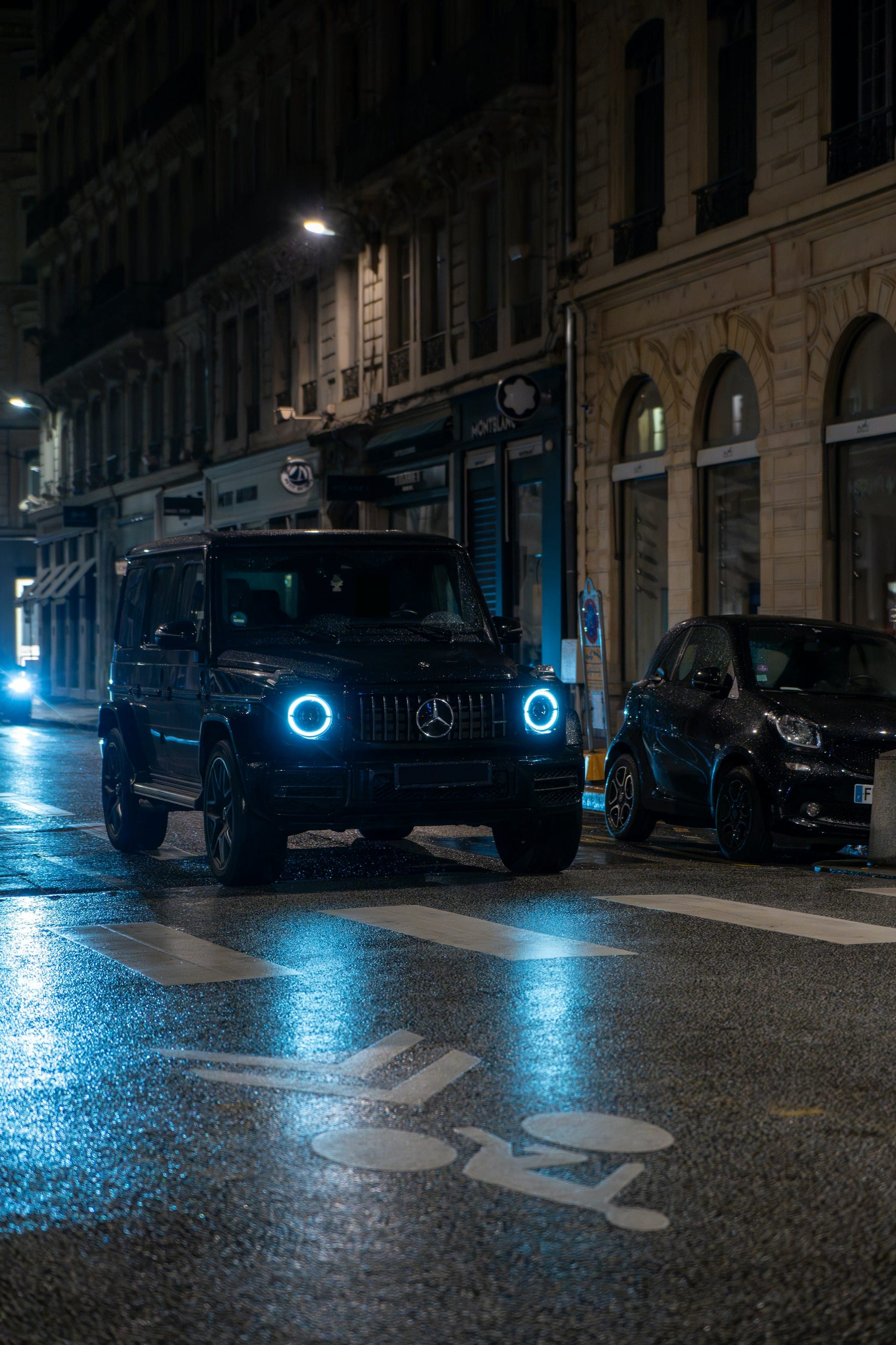 Black escort vehicle on a wet street at night